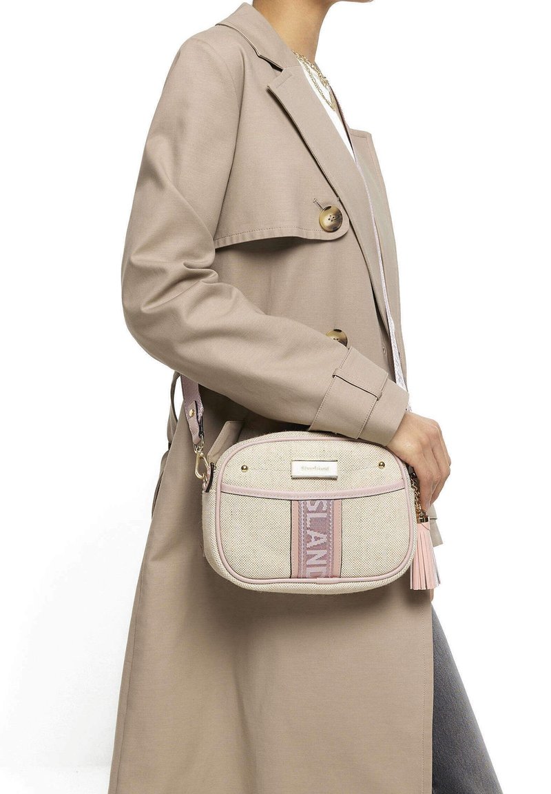 Borsa a tracolla in tessuto beige con accenti rosa, forma arrotondata, dettagli in oro e nappina. Presenta la scritta del marchio in evidenza sul davanti.