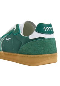 Zelene tenisice s suede stražnjim dijelom, bijelim detaljima, gumenenim đonom i uzdignutim detaljem "1973" na peti, s elegantnim dizajnom.