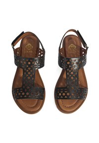 Schwarze Leder-Sandalen mit ausgestanzten, kreisförmigen Mustern, braunem gepolstertem Fußbett und einem Knöchelriemen mit einem goldenen Schnallen-Detail.