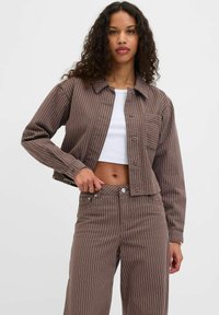 Brown striped denim jacket with a classic collar, front buttons, chest pocket, and paired with matching high-waisted pants.