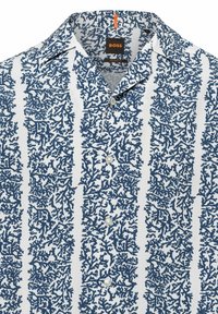 Korte mouwen shirt van witte stof met een blauw koraalpatroon. Ontspannen pasvorm met een puntige kraag en knoopsluiting. Merkenlabel aan de binnenkant.