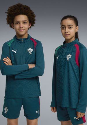 Twee jonge atleten dragen turquoise Portugal voetbaltrainingsshirts en korte broeken met Puma-logo's, staand tegen een grijze achtergrond.