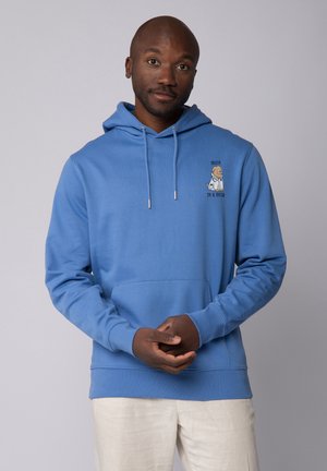 Blauwe hoodie met een voorzak, trekkoordcapuchon en een geborduurde cartoonafbeelding met de tekst "Vertrouw me, ik ben een dokter" op de borst.