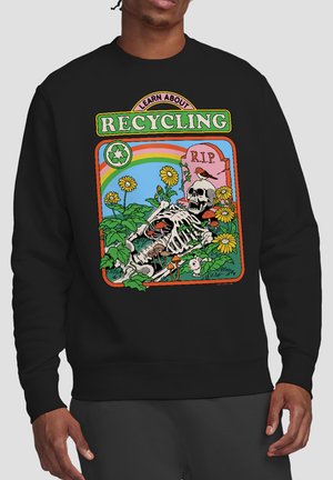 Person trägt schwarzen Pullover mit buntem Motiv eines Skeletts in einem Blumengarten, Grabstein mit der Aufschrift "R.I.P.", Regenbogen und dem Text "Lerne über das Recycling".