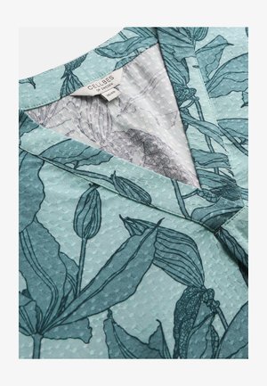 Lys grønblåt tekstureret stof med mørkegrøn botanisk tryk og V-udskæring; tøjmærke med teksten "Cellbes of Sweden 38/40".