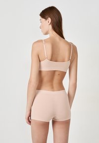 Conjunto de lencería rosa claro que incluye un bralette sencillo y sin costuras con tirantes ajustables y un short a juego con una suave cintura y sin costuras visibles.