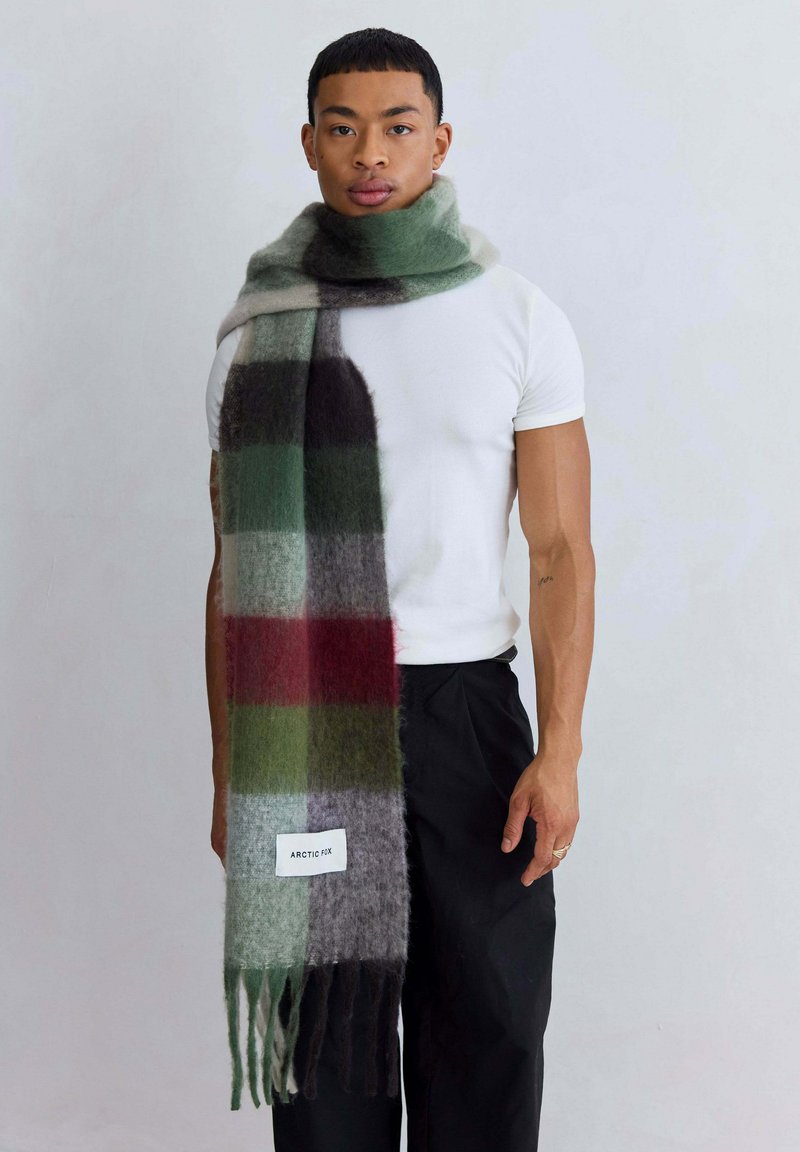 Groene en grijze geruite sjaal met franjes, gemaakt van zacht materiaal. Het label aan de voorkant leest "ARCTIC FX." Casual om de hals gedragen.
