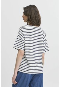 Tricou cu mânecă scurtă, de culoare albă, cu dungi orizontale bleumarin. Are o croială lejeră și un guler rotund, fiind confecționat dintr-un material moale și ușor.