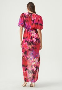 Maxi-jurk in lichte, transparante stof. Heeft een levendige bloemenprint in roze, paars en zwart. Elastische taille, pofmouwen en lange silhouette.