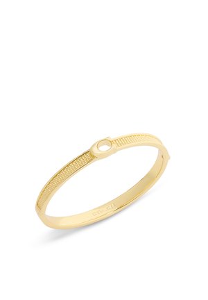Bracelet jonc doré avec détails texturés et fermoir circulaire, gravé du nom de la marque « Coach » à l'intérieur.