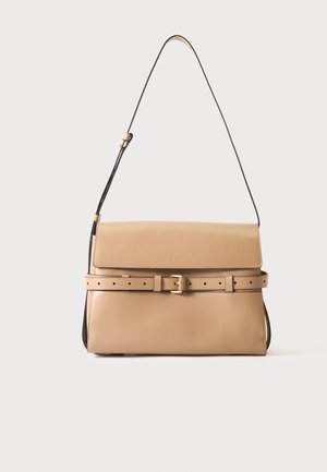 Beige leather handbag with flap closure, slim adjustable shoulder strap, and decorative belt with gold buckle across front.