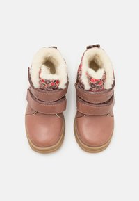 Brune læderstøvler med fleecefor, velcro-stropper og en blomstret kant. Rund tå og gummisål for godt greb.