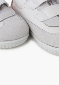 Scarpe per bambini bianche e grigio chiaro, realizzate in pelle e camoscio, dotate di cinturini in velcro, superfici testurizzate e suole di gomma.
