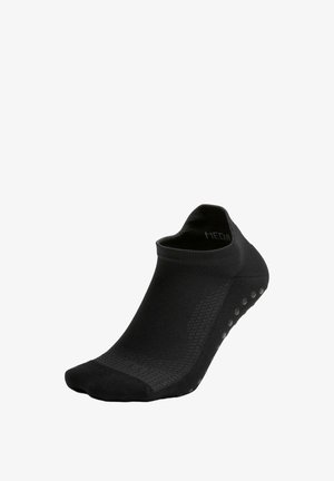 Calcetín negro hasta el tobillo hecho de una tela suave y elástica. Cuenta con agarre texturizado en la suela y un diseño de corte bajo sin logotipos visibles.