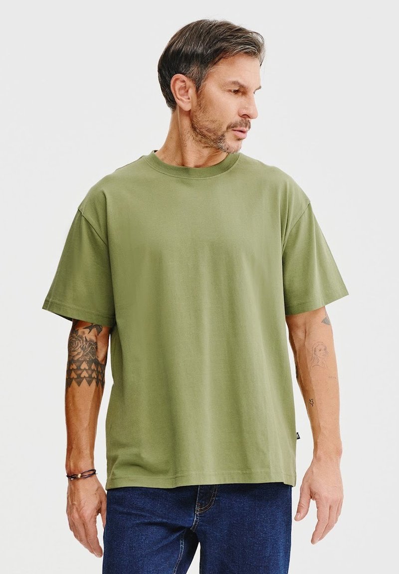 Oliwkowa bawełniana koszulka z okrągłym dekoltem i krótkimi rękawami, o luźnym kroju i minimalistycznym designie.