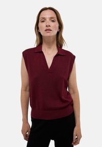 Débardeur bordeaux sans manches avec un col en V, en tissu texturé et ourlet côtelé. Il présente un col classique et une coupe décontractée.