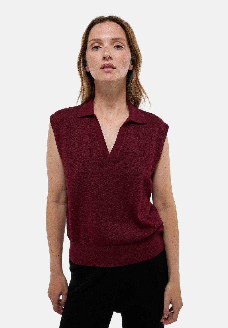 Débardeur bordeaux sans manches avec un col en V, en tissu texturé et ourlet côtelé. Il présente un col classique et une coupe décontractée.