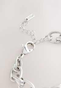 Silver chain necklace featuring large links and a lobster clasp. The surface has a polished finish, highlighting its reflective texture.