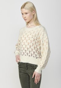 Pulover tricotat de culoare crem, cu o textură moale și pufoasă, având un model de fluturi mici colorați în nuanțe de piersică și purpuriu.