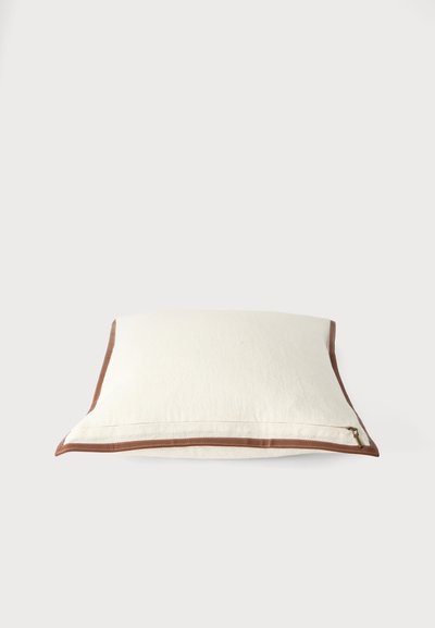 Oreiller blanc rectangulaire avec bordure marron et une fermeture éclair visible sur un côté, présenté sur un fond clair uni.