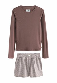 Langärmliges mauvefarbenes Oberteil mit gerippter Textur, kombiniert mit karierten, leichten Shorts in Braun und Creme. Beide Teile haben einen lässigen Schnitt.