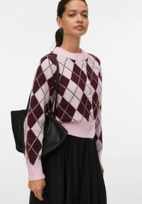 Svetr s argyle vzorem v růžových a burgundských odstínech, s kulatým límečkem, zapínáním na knoflíky a vroubkovanými manžetami, spárovaný s černou taškou.