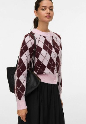 Cardigan à motif argyle dans des teintes de rose et de bordeaux, avec un col rond, une fermeture à boutons et des poignets côtelés, associé à un sac noir.