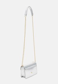 Silver metallic crossbody bag with a smooth texture, fold-over flap, gold chain strap, and small gold accent on the front.