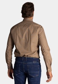Bruine geblokte overhemden met een spread collar, met kleine geometrische patronen. Draag het met donkerblauwe jeans en een geweven riem.