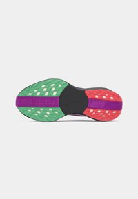 La semelle des chaussures Nike présente une base noire, avec des accents verts, rouges et violets. Caoutchouc texturé avec des motifs variés pour une meilleure adhérence.