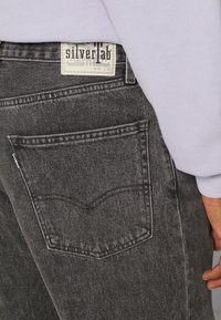 Svarta jeans i denim med en klassisk 5-ficksdesign, utrustade med en synlig etikett och sömdetaljer. Texturerat tyg med en lätt urblekt finish.