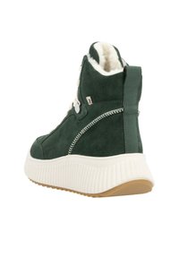 Bottines en suède vert avec doublure en fausse fourrure blanche, lacets blancs et semelle texturée crème. Présente un petit logo sur le côté.