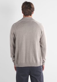 Pull en maille gris avec une finition texturée, des poignets et un ourlet côtelés, et un col rond, vu de dos, avec une coupe ample.