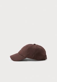 Brun bomull baseballkeps med böjd skärm, sydda hål för ventilation och en justerbar rem baktill.