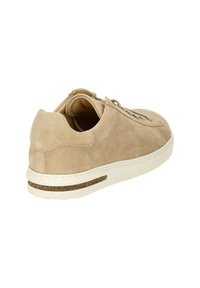 Sneaker in suede beige con punta tonda, design con lacci e suola bianca caratterizzata da un sottile accento in sughero sul lato. Tessuto morbido e cuciture minime.