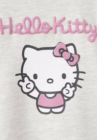 Hanorac alb cu o grafică roz "Hello Kitty". Personajul poartă o fundă roz, contururi negre și o postură drăguță, având o textură moale a țesăturii.