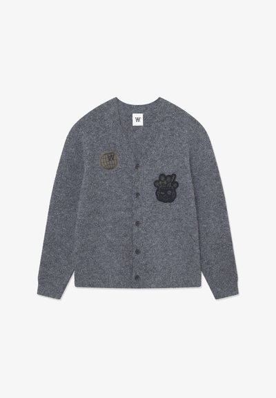 Grijze cardigan van zachte stof, met zwarte geborduurde patches: een wereldbol en een karakter, met een knoopsluiting aan de voorkant.
