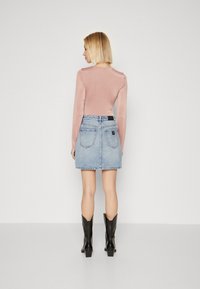 Top en velours rose à manches longues associé à une jupe en denim bleu clair. Des bottes noires jusqu'aux genoux complètent la tenue. Design simple, style décontracté.