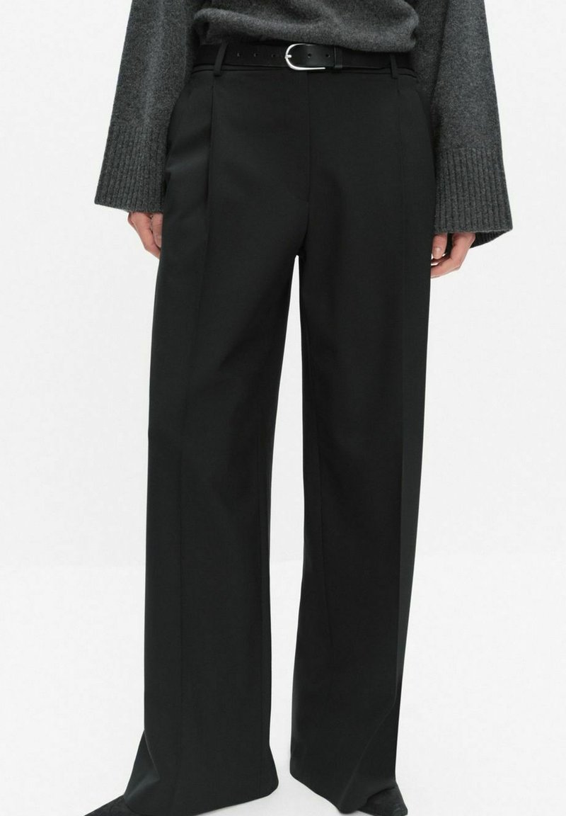 Czarne, dopasowane spodnie z wysokim stanem, szerokimi nogawkami i fałdami z przodu. Materiał ma gładką fakturę; stylizowane z cienkim paskiem.