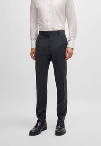 Dark grey tailored trousers with a smooth texture, featuring a flat front design, side pockets, and belt loops, paired with black shoes.