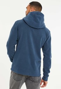 Marineblauwe fleece hoodie met een grote capuchon, lange mouwen en een rechte zoom, met een gladde textuur en minimale details.