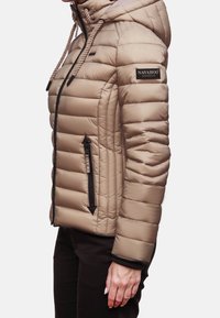 Beige pufferjakke med hætte, der har vandrette quiltede paneler, frontlynlåslommer og et logo-patch på venstre ærme.