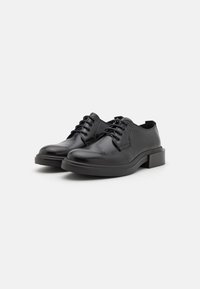 Black leather shoes with a glossy finish, lace-up design, round toe, and a low block heel; textured soles for grip.