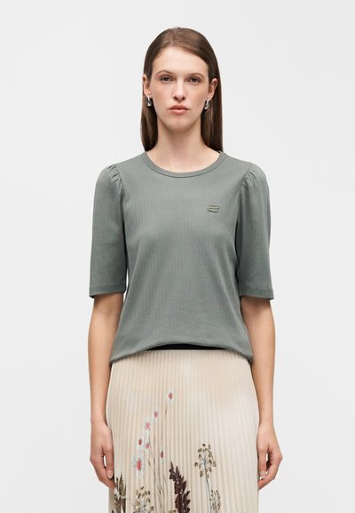 Ανοιχτό πράσινο ριμπ μπλουζάκι με κοντά φουσκωτά μανίκια και στρογγυλή λαιμόκοψη, με μικρό κέντημα λογότυπου στο στήθος.