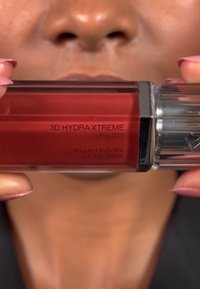 Red lip gloss in a rectangular clear container with a silver cap. Label reads "3D HYDRA XTREME LIPGLOSS" in black text. Smooth texture.