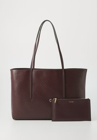 Bordeaux leren tote bag met een gestructureerd ontwerp, voorzien van lange handvatten en een bijpassende ritstas met gouden hardware accenten.