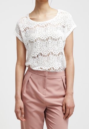Top bianco in pizzo con maniche corte, caratterizzato da un design scallop e sezioni trasparenti. Abbinato a pantaloni tailored rosa chiaro.