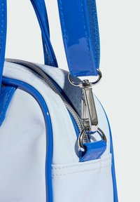 Niebieska lakierowana torebka ze skóry z białymi akcentami, zamykana na zamek błyskawiczny, z srebrnymi okuciami i teksturowanym paskiem.