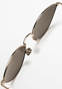 Gold metallic frame sunglasses with oval dark lenses, featuring a bridge connector and slim temples for a lightweight design.