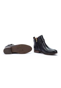Bottes noires en cuir à la cheville avec une fermeture éclair latérale, un petit talon et une semelle marron texturée avec un motif subtil. Fini lisse et détails minimaux.